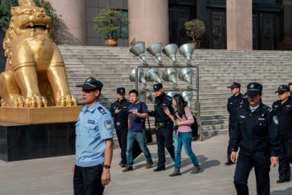 Xu Yan, wife of human rights lawyer Yu Wensheng, and her lawyer Xie Yang are being escorted to the exit by security personnel in 2019 | Nicolas Asfouri/AFP via Getty Images