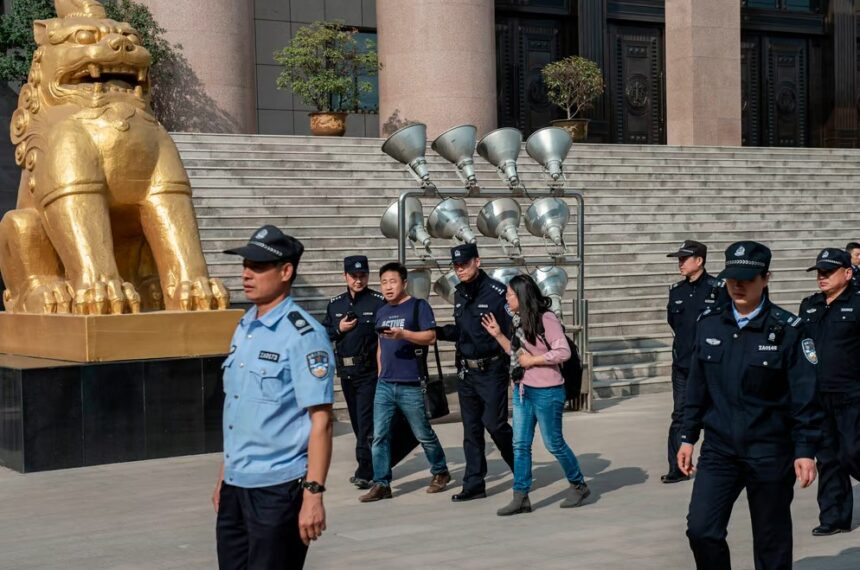 Xu Yan, wife of human rights lawyer Yu Wensheng, and her lawyer Xie Yang are being escorted to the exit by security personnel in 2019 | Nicolas Asfouri/AFP via Getty Images