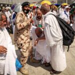 A policeman and other pilgrims help a worshipper affected by the scorching heat © FADEL SENNA / AFP