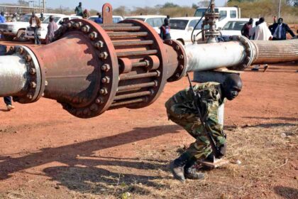A soldier crossing under a pipeline.