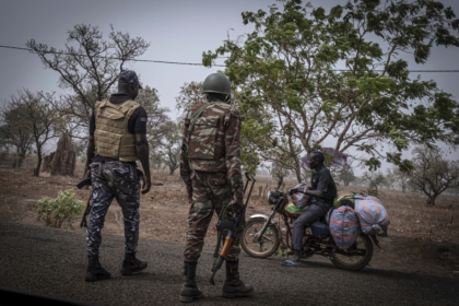 FILE - A police officer and a soldier from Benin stop a motorcyclist at a checkpoint outside Porga, Benin, March 26, 2022. Jihadi fighters who had long operated in Africa’s volatile Sahel region have settled in northwestern Nigeria after crossing from neighboring Benin, a new report said Wednesday, June 19, 2024, the latest trend in the militants’ movements to wealthier West African coastal nations. (AP Photo/ Marco Simoncelli, File)