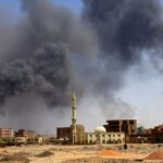 A man walks as smoke rises over buildings following air strikes during clashes between the paramilitary Rapid Support Forces and the Sudanese army in Khartoum North on May 1, 2023. File | Reuters