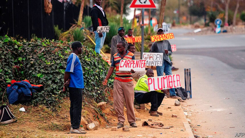 Job seekers wait beside a road for casual work offered by passing motorists