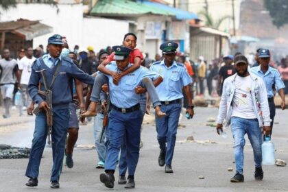 A Mozambican policeman carrying an injured child "national shutdown" against the election outcome in Maputo, Mozambique