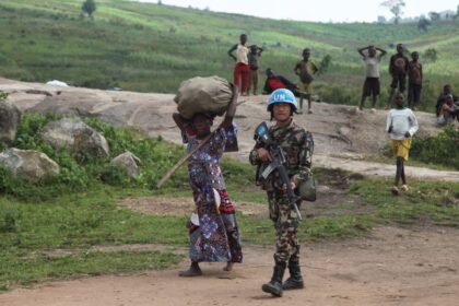 A Nepalese peacekeeper from the United Nations Organization Stabilization Mission in the Democratic Republic of the Congo (MONUSCO) escorts an internally displaced Congolese woman returning from the fields carrying a bag of her harvest on her head, as part of the secure harvest operation within Fataki, in Ituri province, near North Kivu province of the Democratic Republic of Congo December 12, 2024. REUTERS/Djaffar Al Katanty